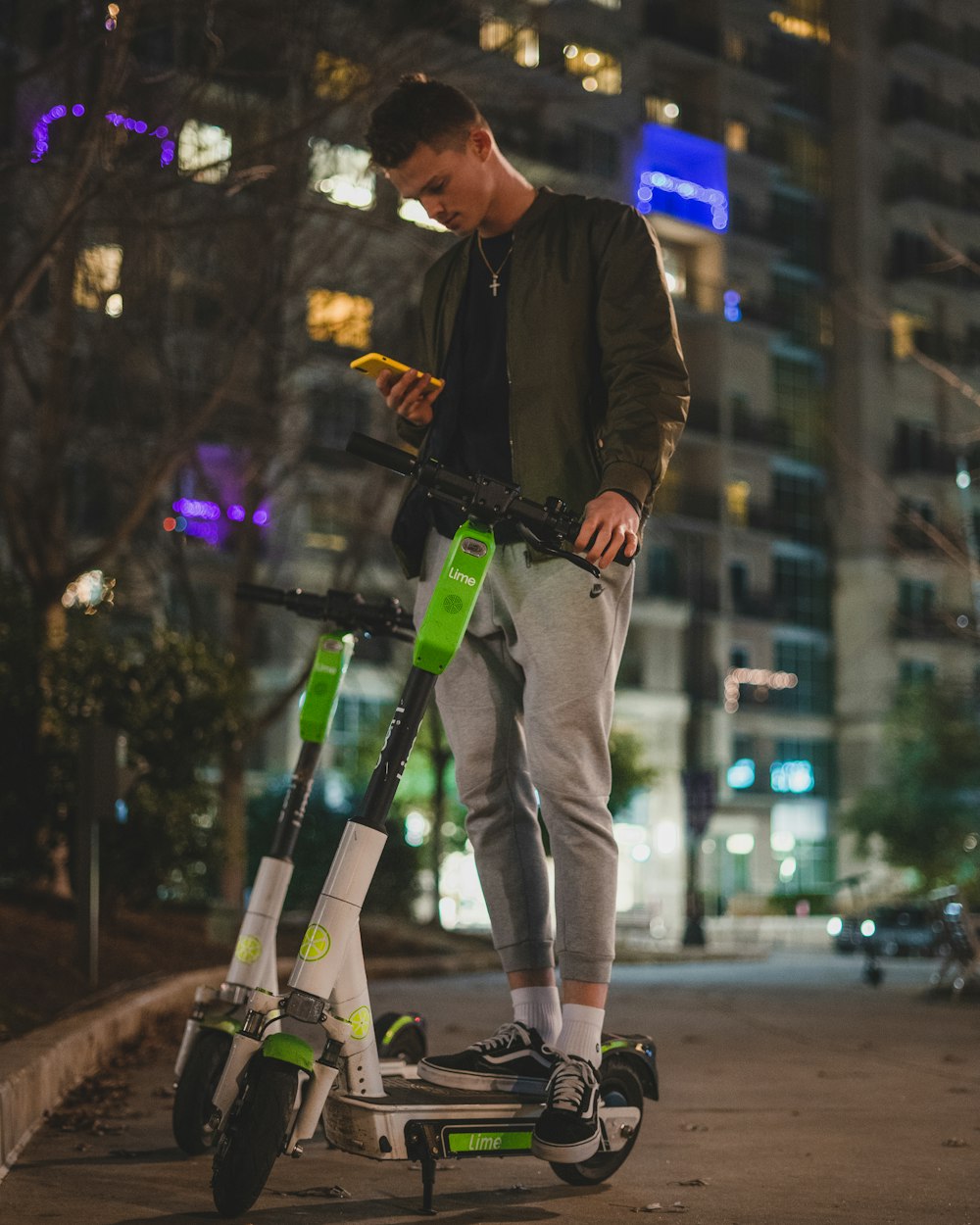 man standing on white, green, and black electric scooter during nighttime