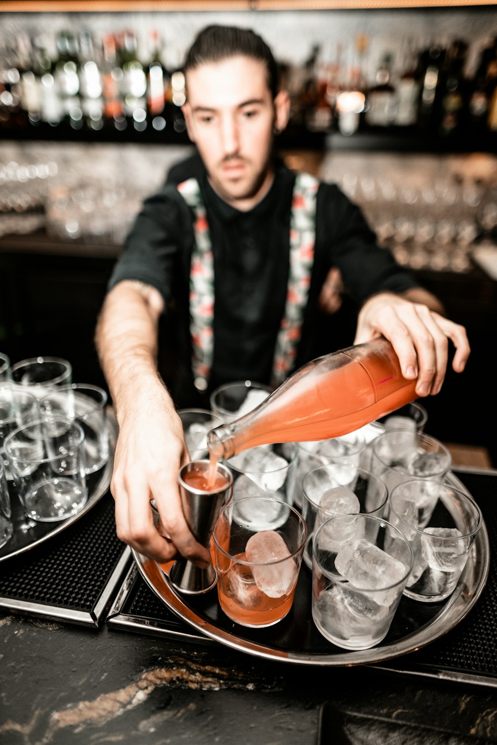 man pouring wine on shot glasses