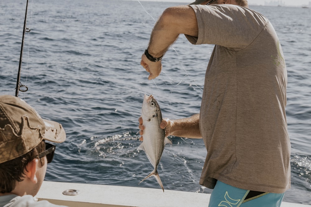 person holding gray and white fish on boat