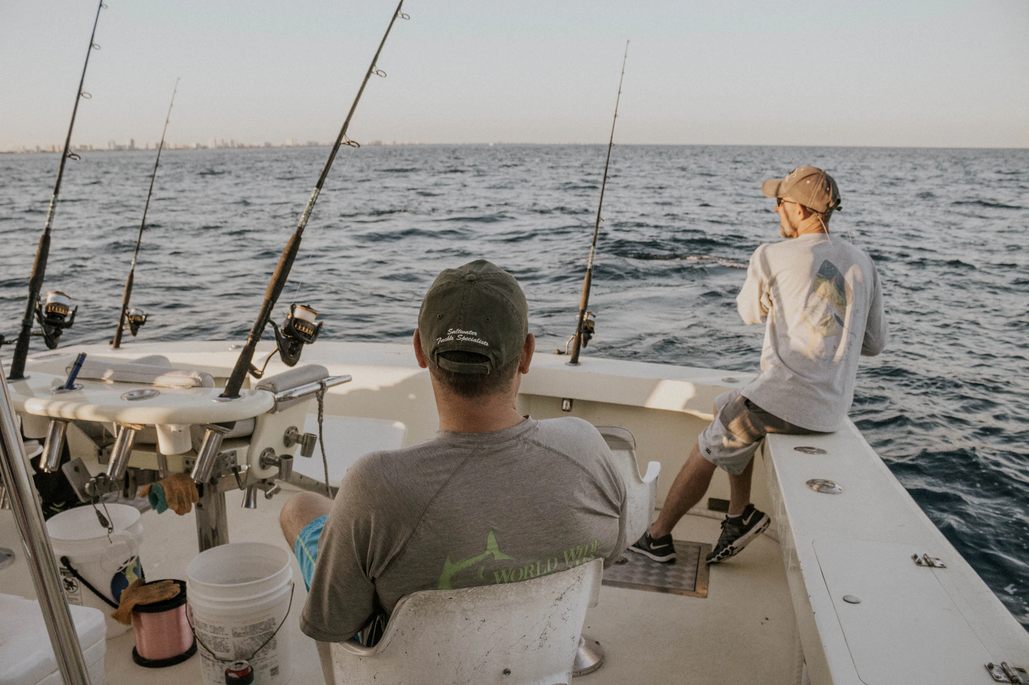 Anglers fishing from a private boat rigged with rods on open blue water
