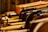 A close-up view of multiple violins arranged side by side, with their bows resting on top. The warm wooden tones create an artistic composition, emphasizing the craftsmanship of the instruments.