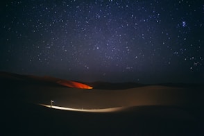 a person standing in the middle of a desert at night