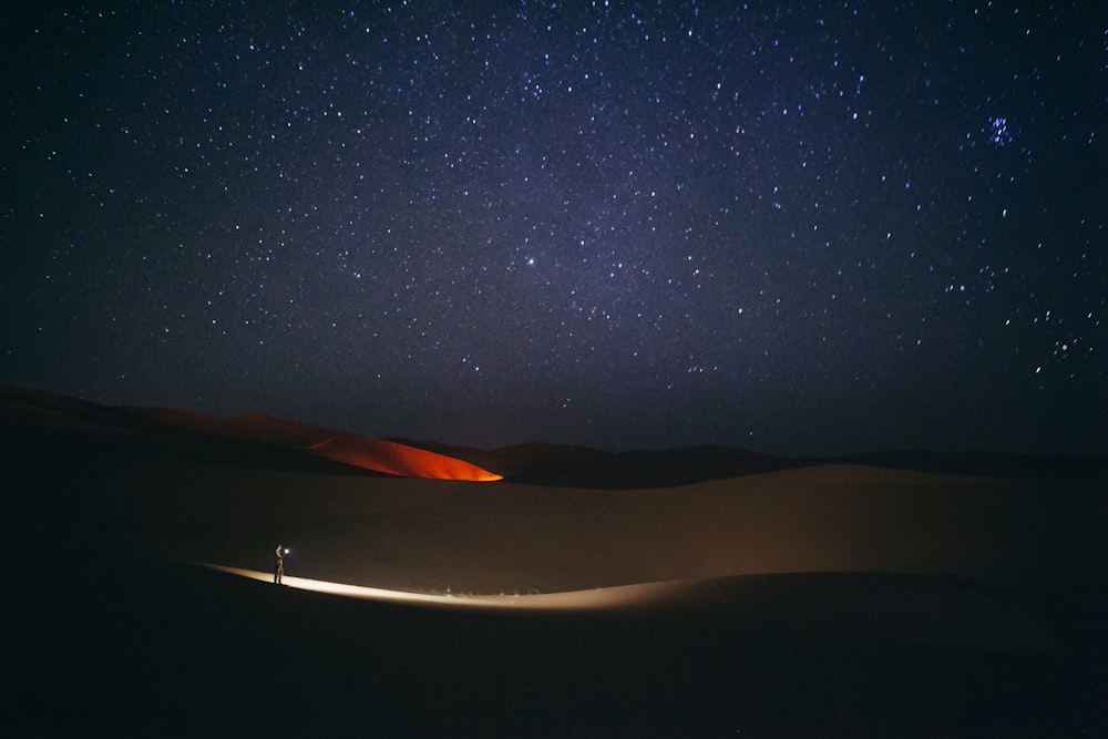 a person standing in the middle of a desert at night