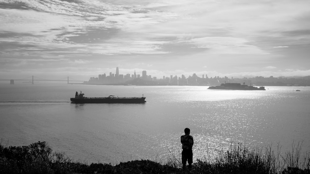 grayscale photography of man standing near sea