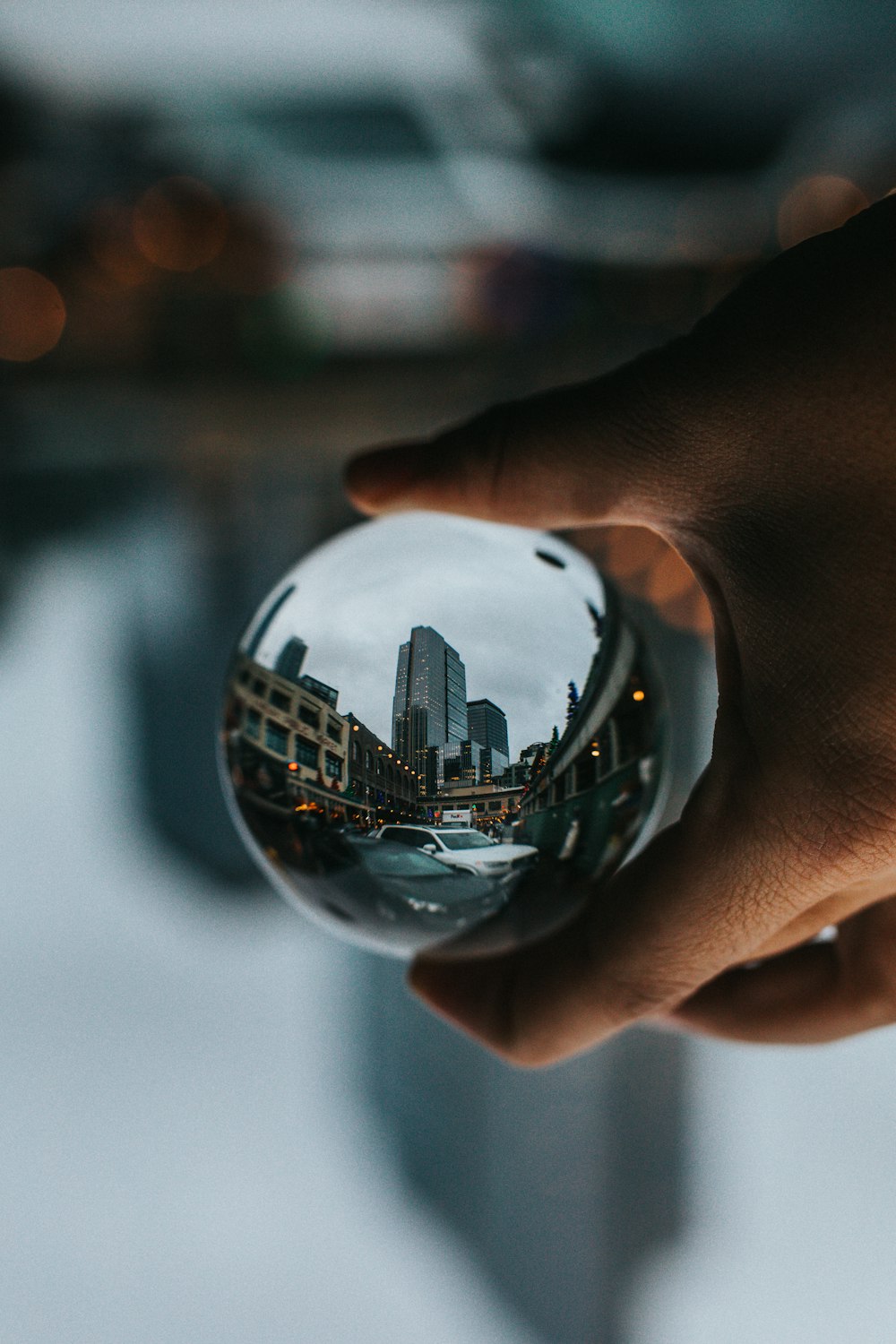 clear ball reflecting buildings and cars