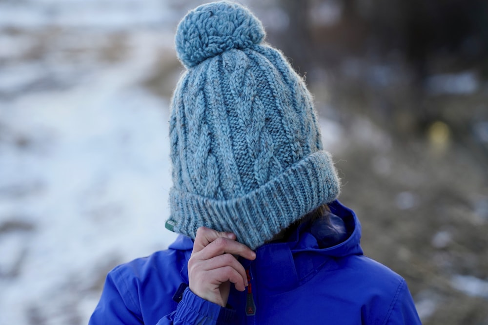 Frau bedeckt ihr Gesicht mit Strickmütze