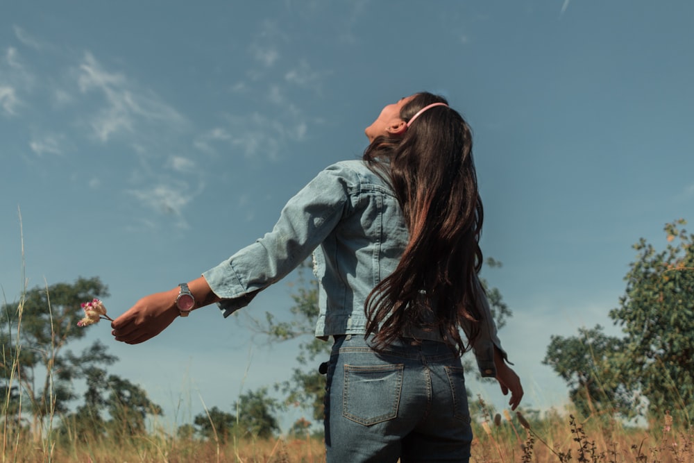 a woman standing in a field with her arms outstretched