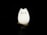 A hand is holding a glowing cat-shaped lamp in a dark environment. The lamp has a cute, minimalistic design with simple facial features, giving it a playful and whimsical appearance. The light from the lamp softly illuminates the hand supporting it.