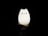 A hand is holding a glowing cat-shaped lamp in a dark environment. The lamp has a cute, minimalistic design with simple facial features, giving it a playful and whimsical appearance. The light from the lamp softly illuminates the hand supporting it.