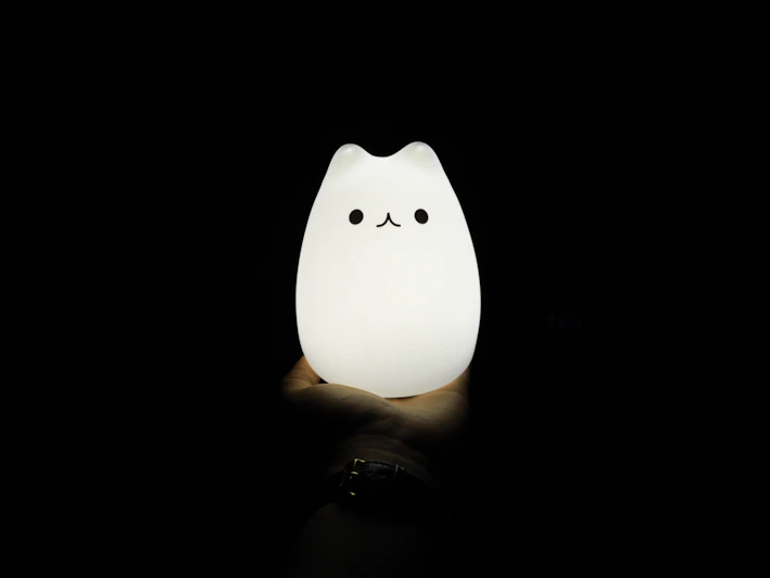 Close-up of a 3D printed litophany lamp featuring a detailed anime character design glowing softly in a dark room