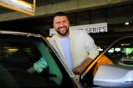 A chauffeur opening the door of a luxury vehicle for a smiling passenger at Gatwick Airport.