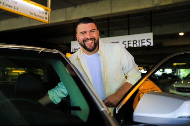 A friendly driver opening a car door to welcome travelers after a long flight.