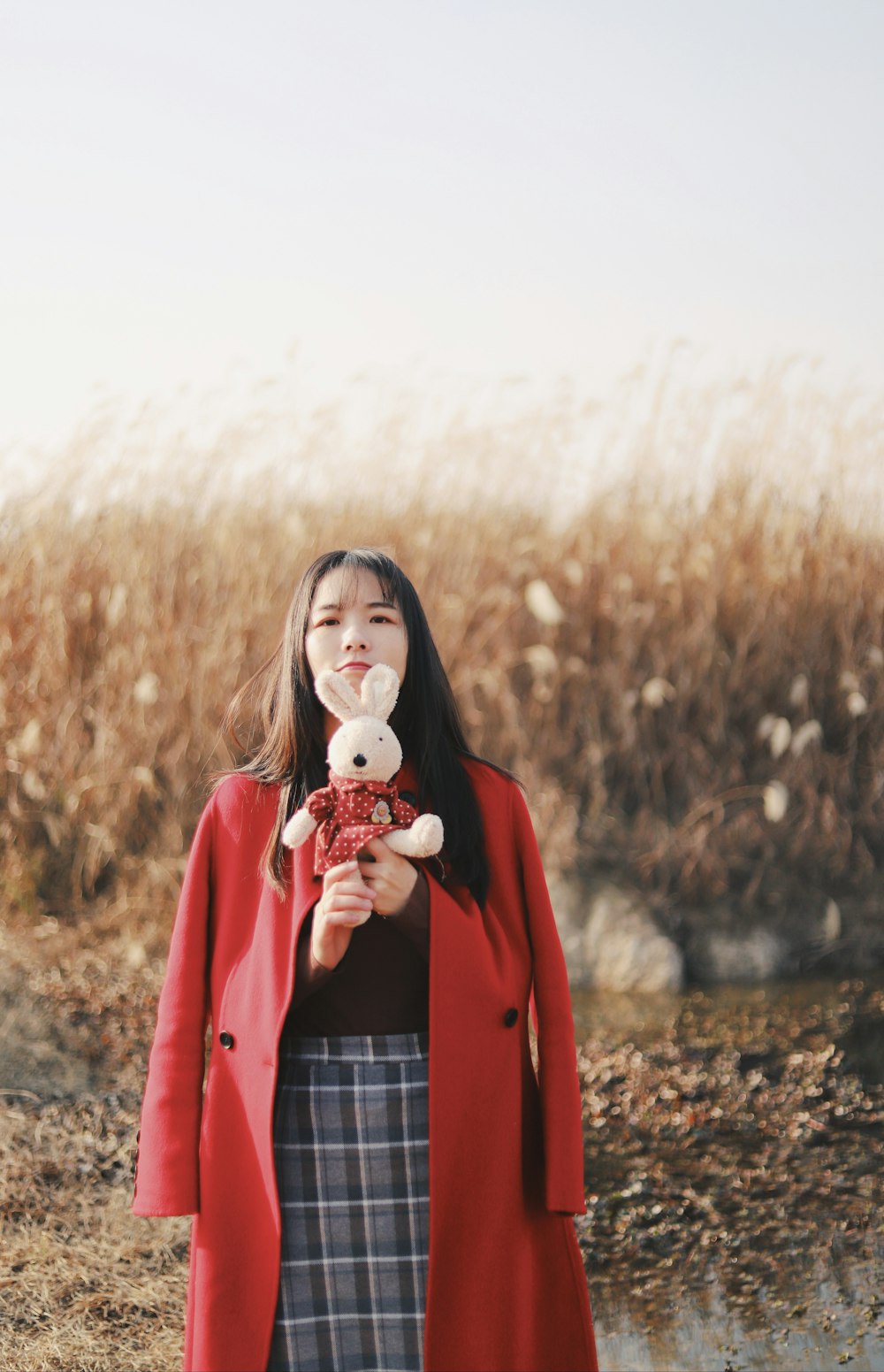 woman in red red coat holding rabbit plush toy