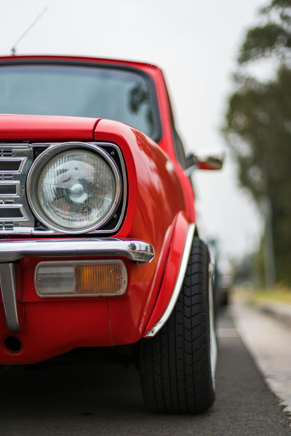 selective focus photography of red car parked beside curb during daytime