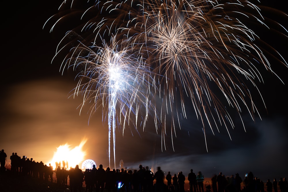 people watching bonfire and fireworks during night