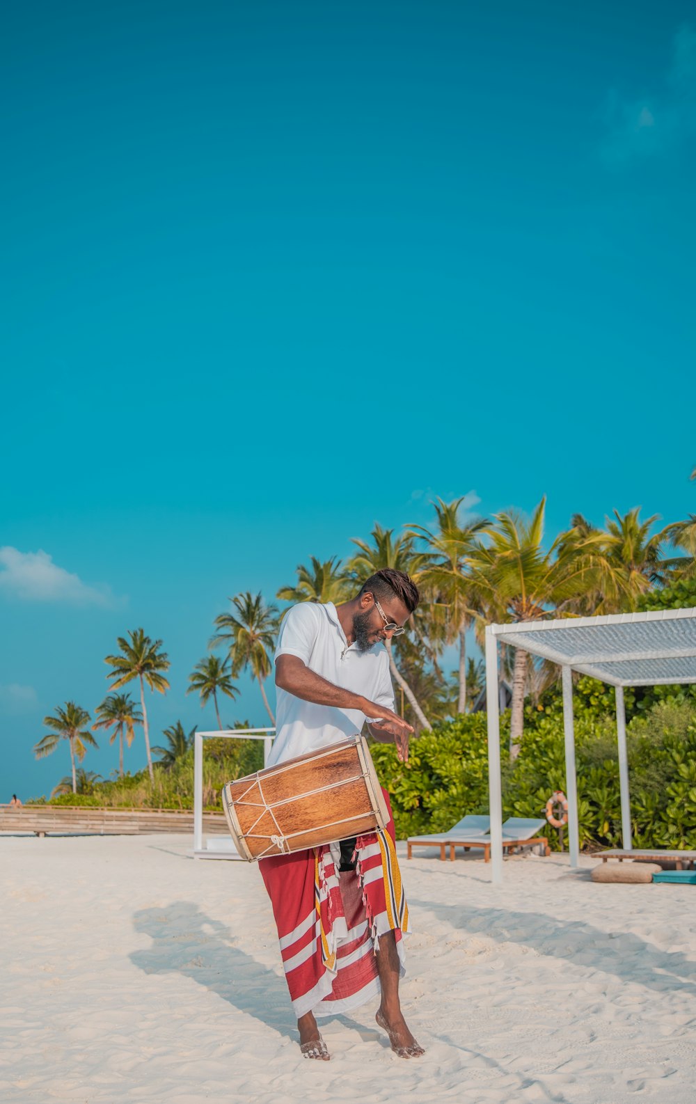man carrying brown drum on beach