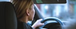 a woman sitting in a car with a steering wheel