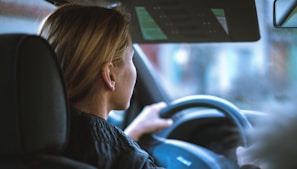 a woman sitting in a car with a steering wheel