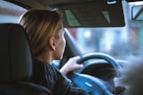 a woman sitting in a car with a steering wheel