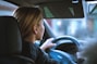 a woman sitting in a car with a steering wheel