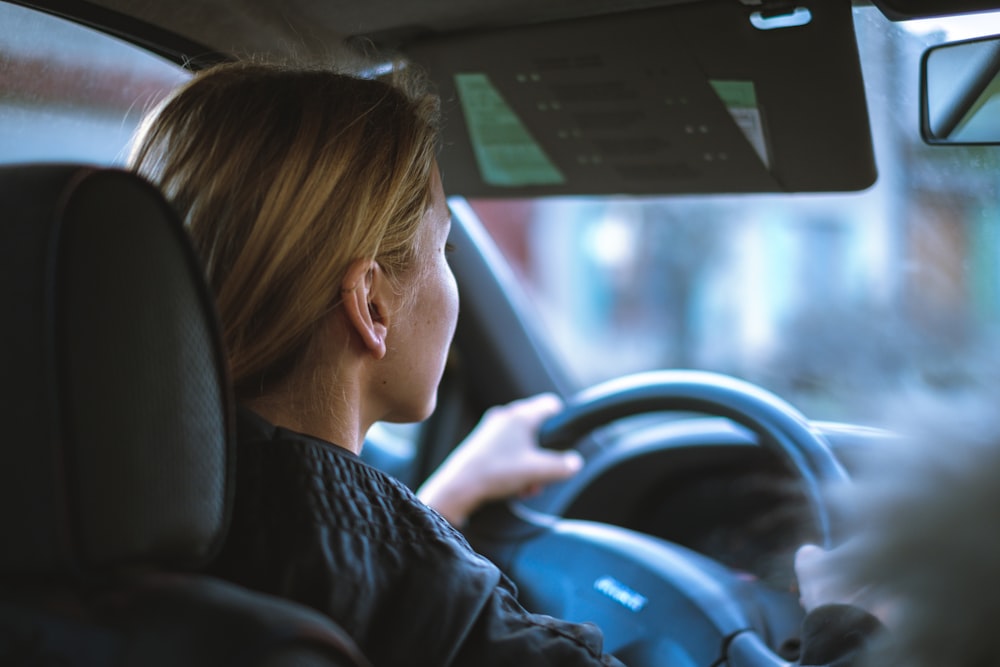 a woman sitting in a car with a steering wheel