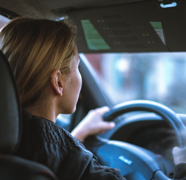 a woman sitting in a car with a steering wheel