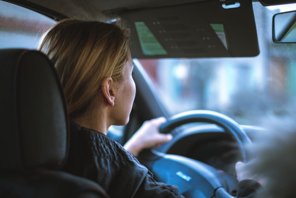 uma mulher sentada em um carro com um volante