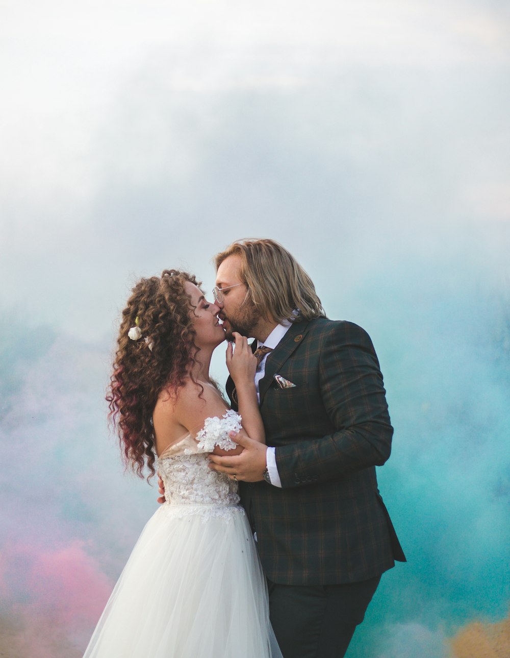 a bride and groom kissing in front of a cloud of smoke