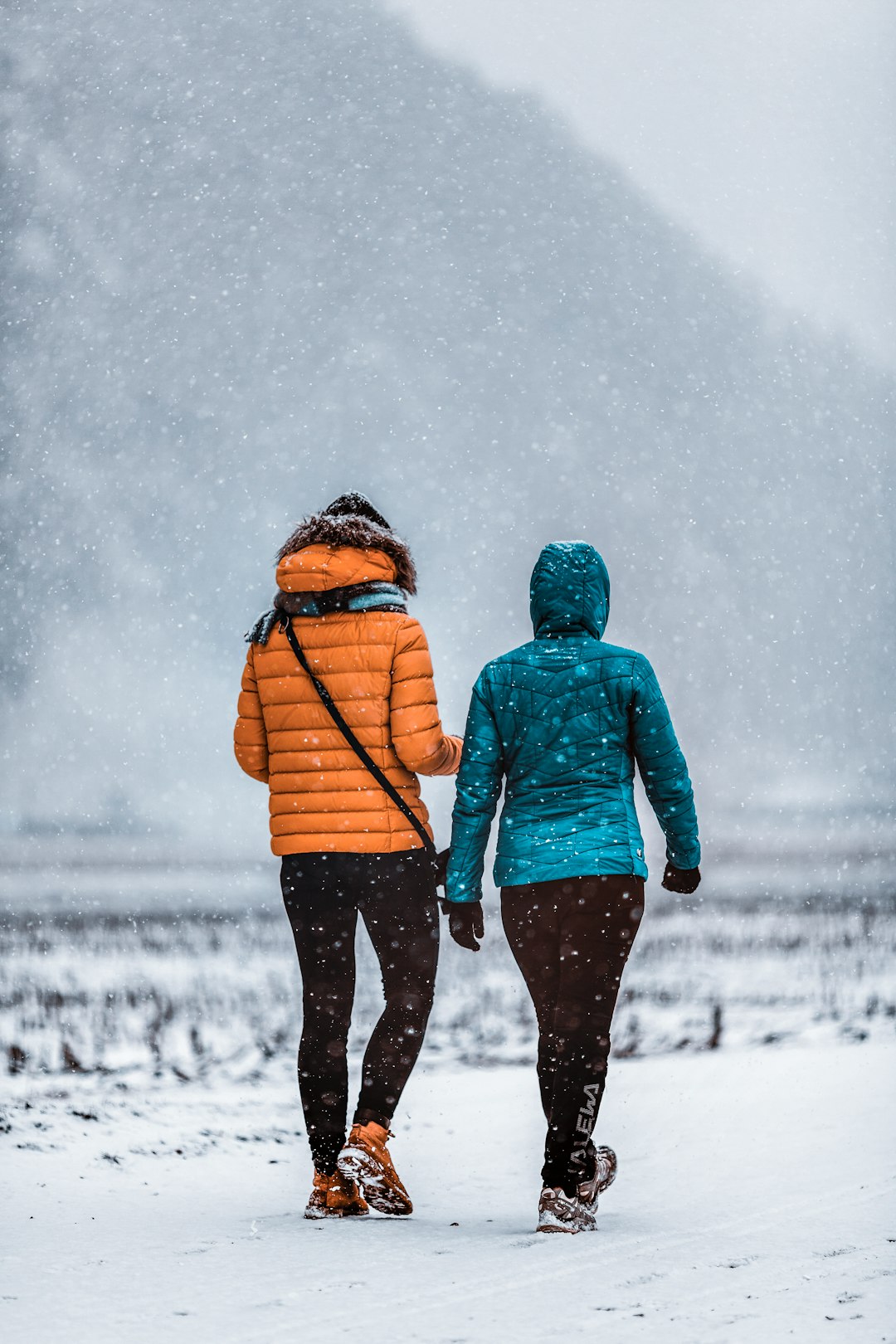man and woman walking on snow covered ground