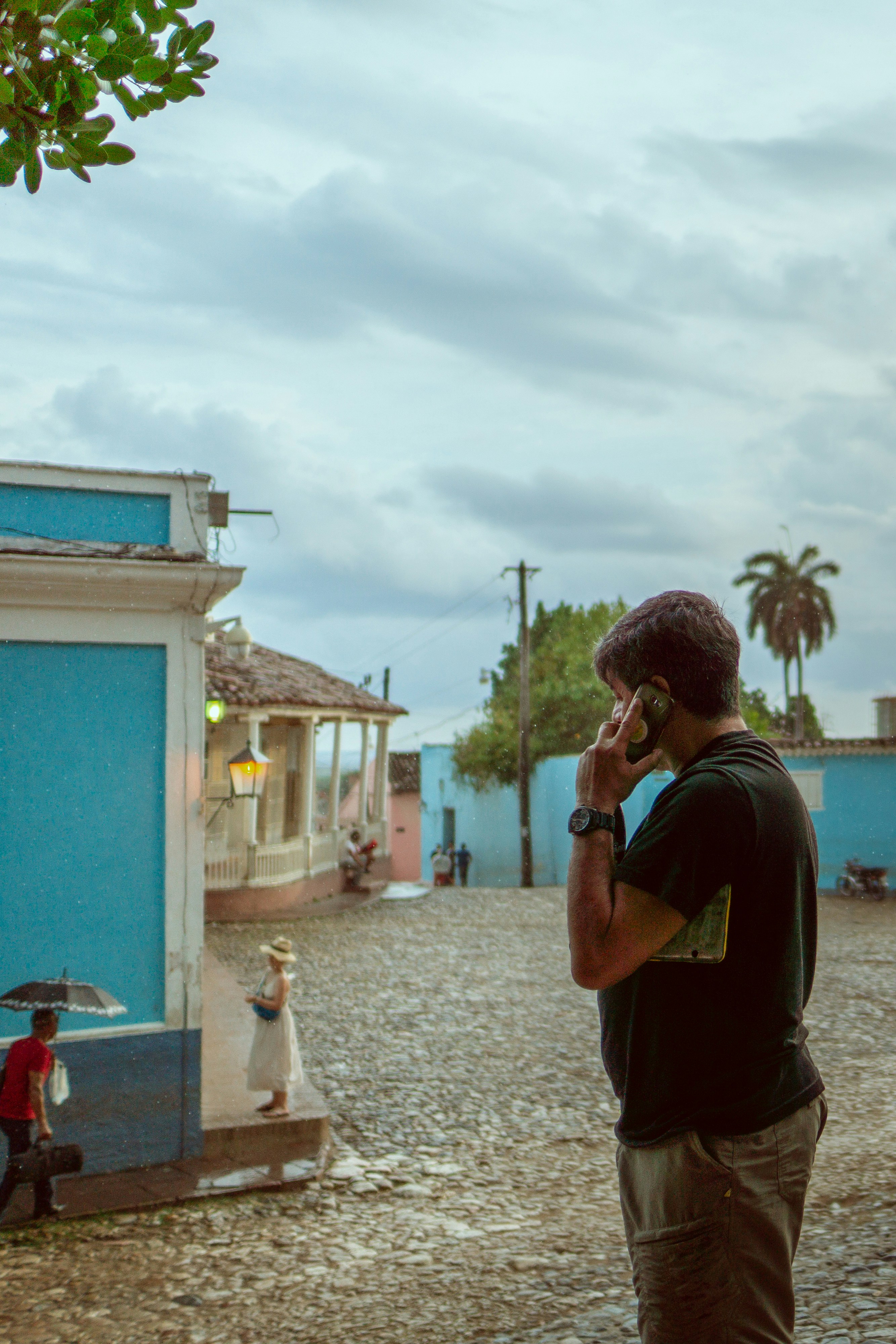 man wearing black crew-neck t-shirt using phone while standing on road