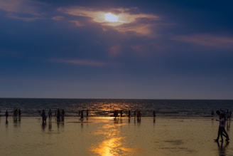 silhouette of crowd on seashore during golden hour
