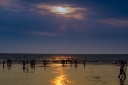 silhouette of crowd on seashore during golden hour