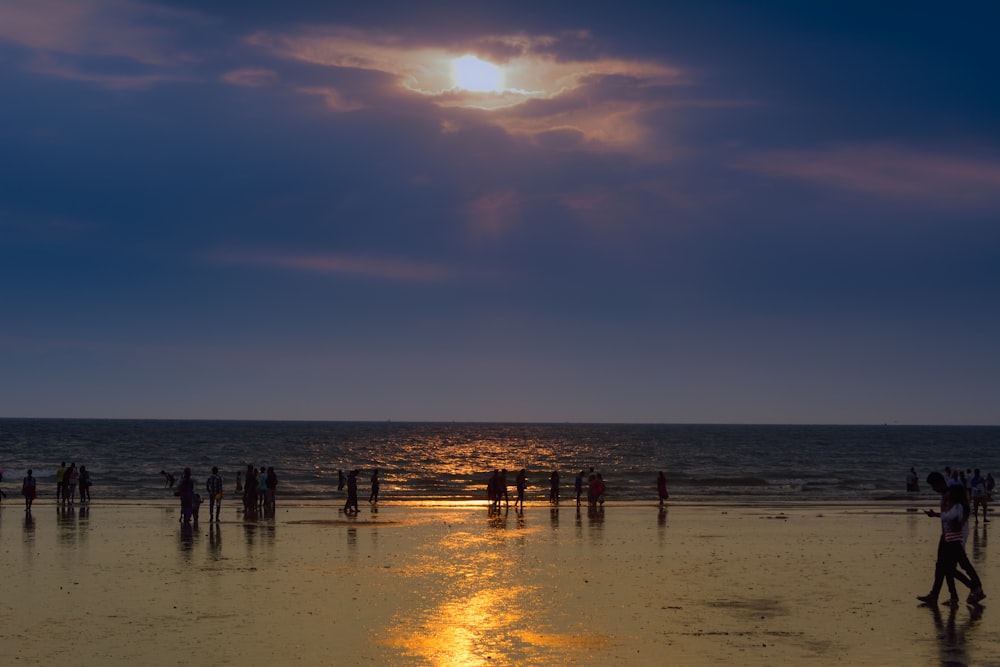 silhouette of crowd on seashore during golden hour