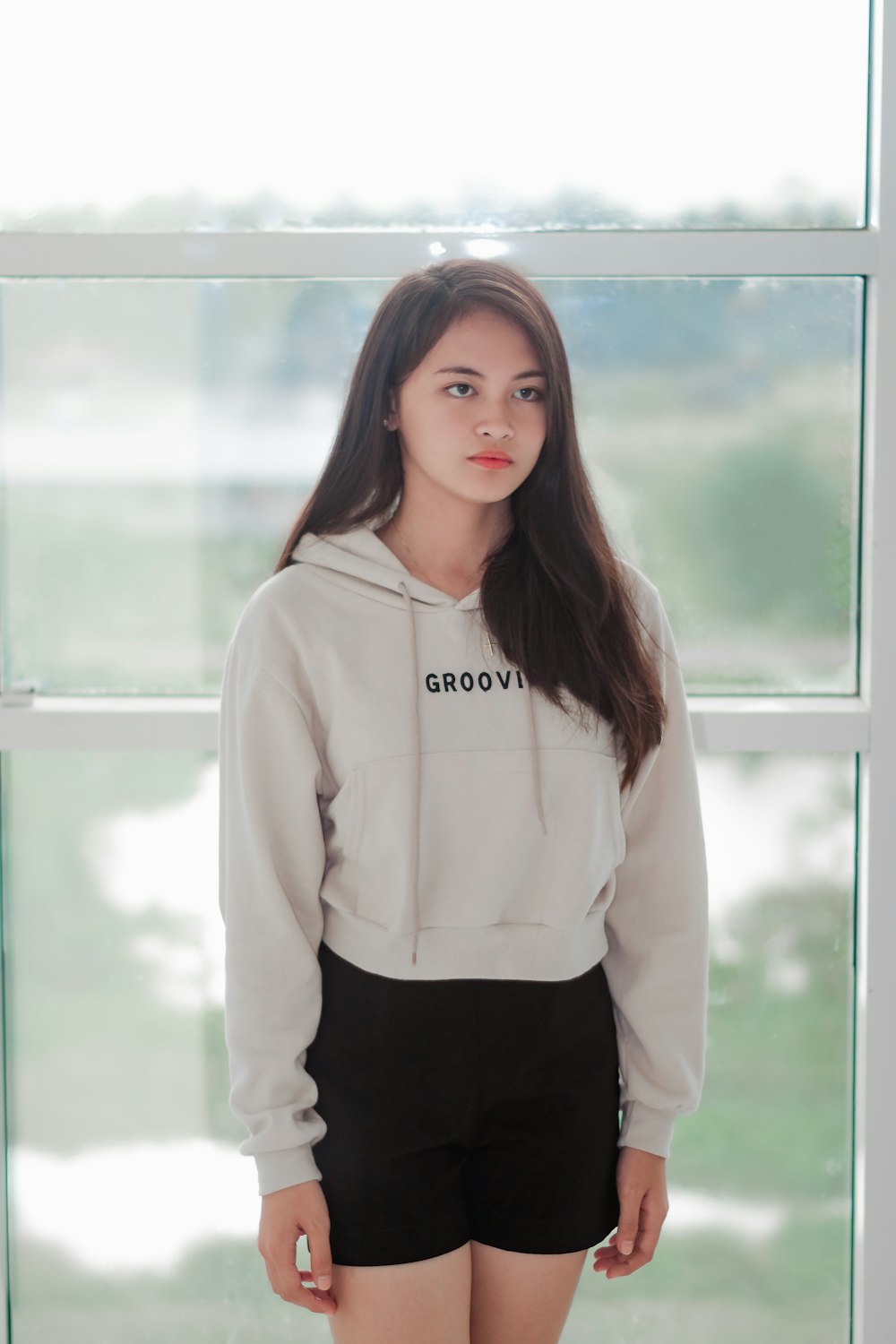 woman wearing white pullover hoodie standing near clear glass wall