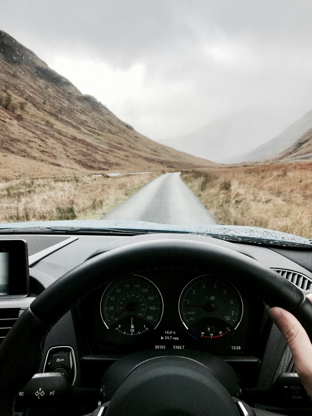 person riding inside vehicle near mountain during daytime