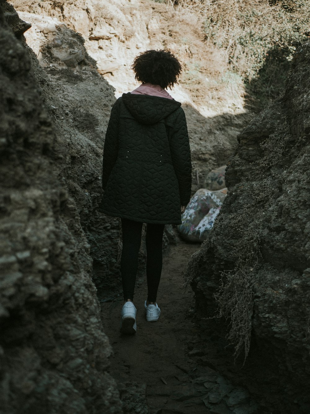 woman walking beside rocky walls