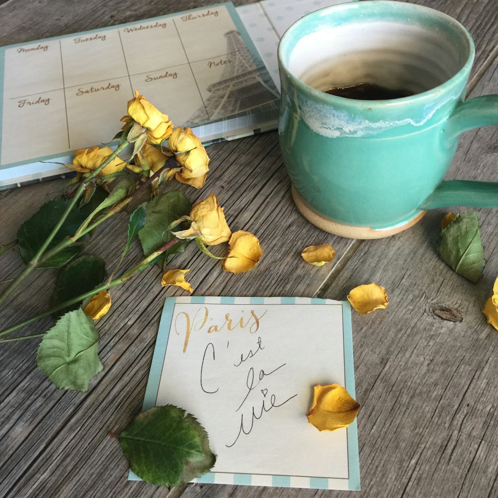 yellow flowers beside teal ceramic mug