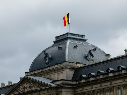 gray and white building with red, yellow, and black striped flag on roof in Brussels Park Belgium
