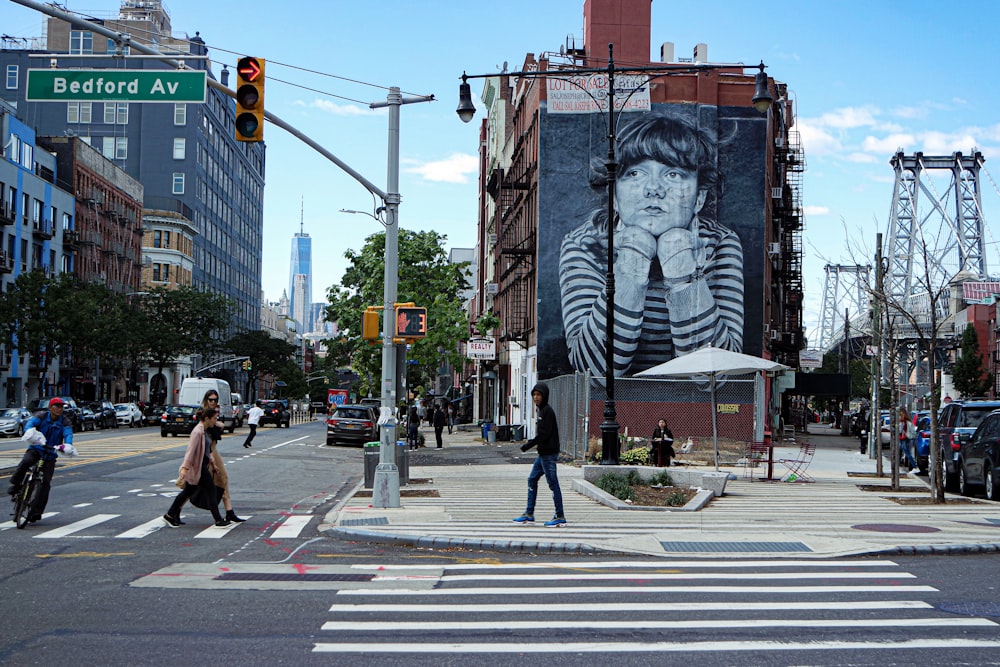 uma mulher atravessando uma rua em frente a um grande quadro