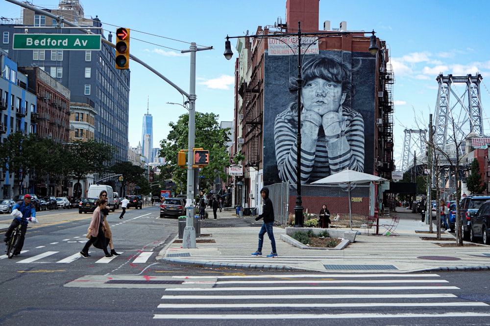a woman crossing a street in front of a large painting