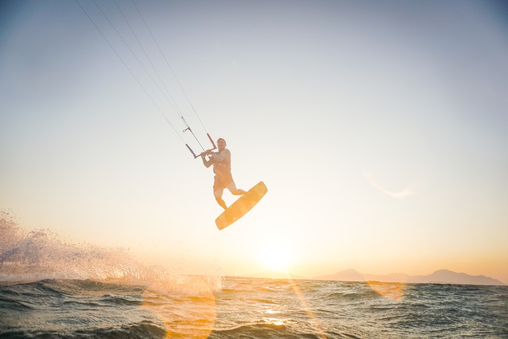 man parasailing at the ocean during golden hour