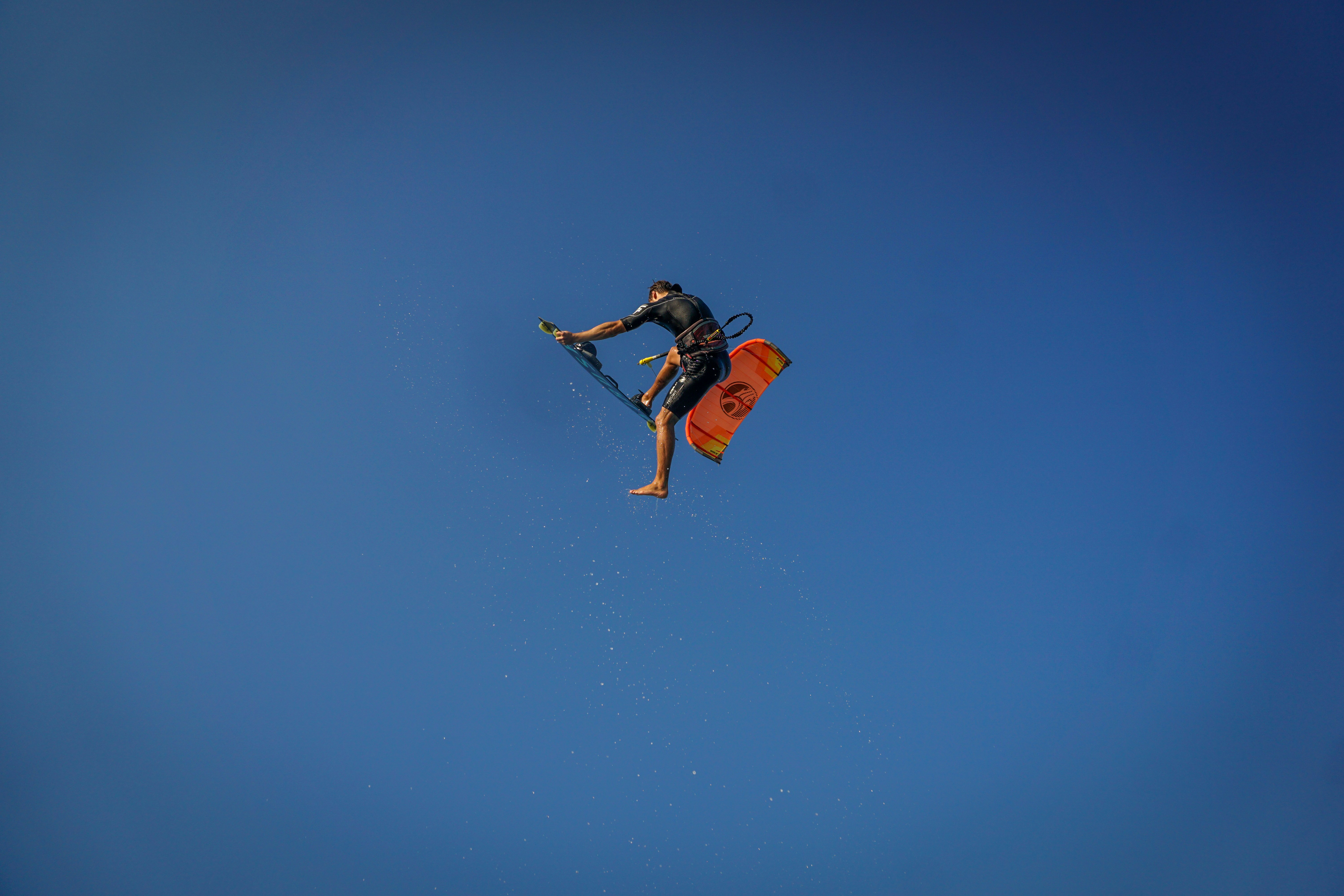 man in mid air holding wakeboard during day