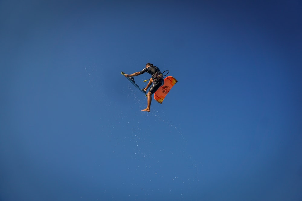 man in mid air holding wakeboard during day