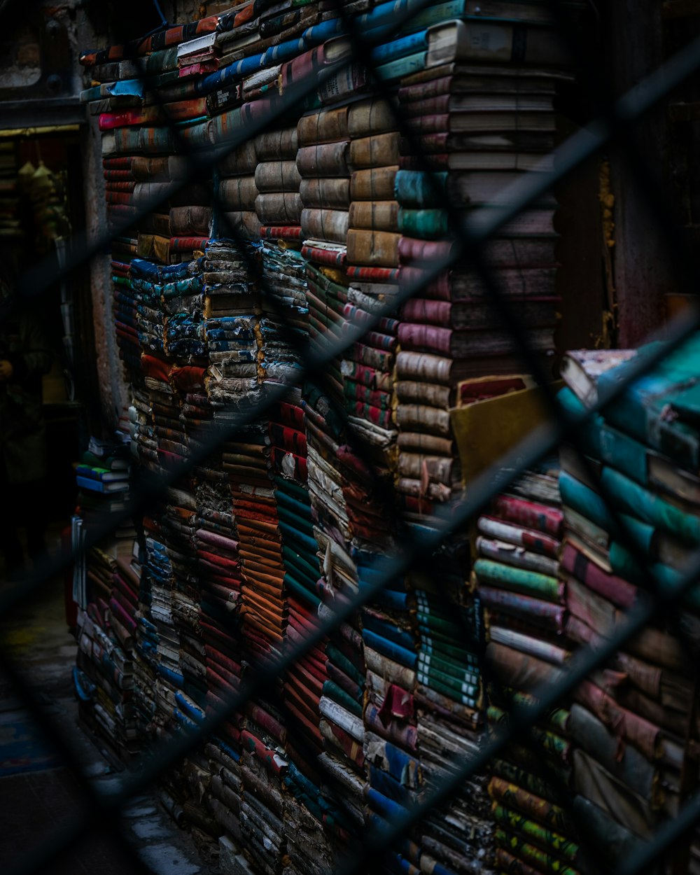 a large stack of books behind a chain link fence