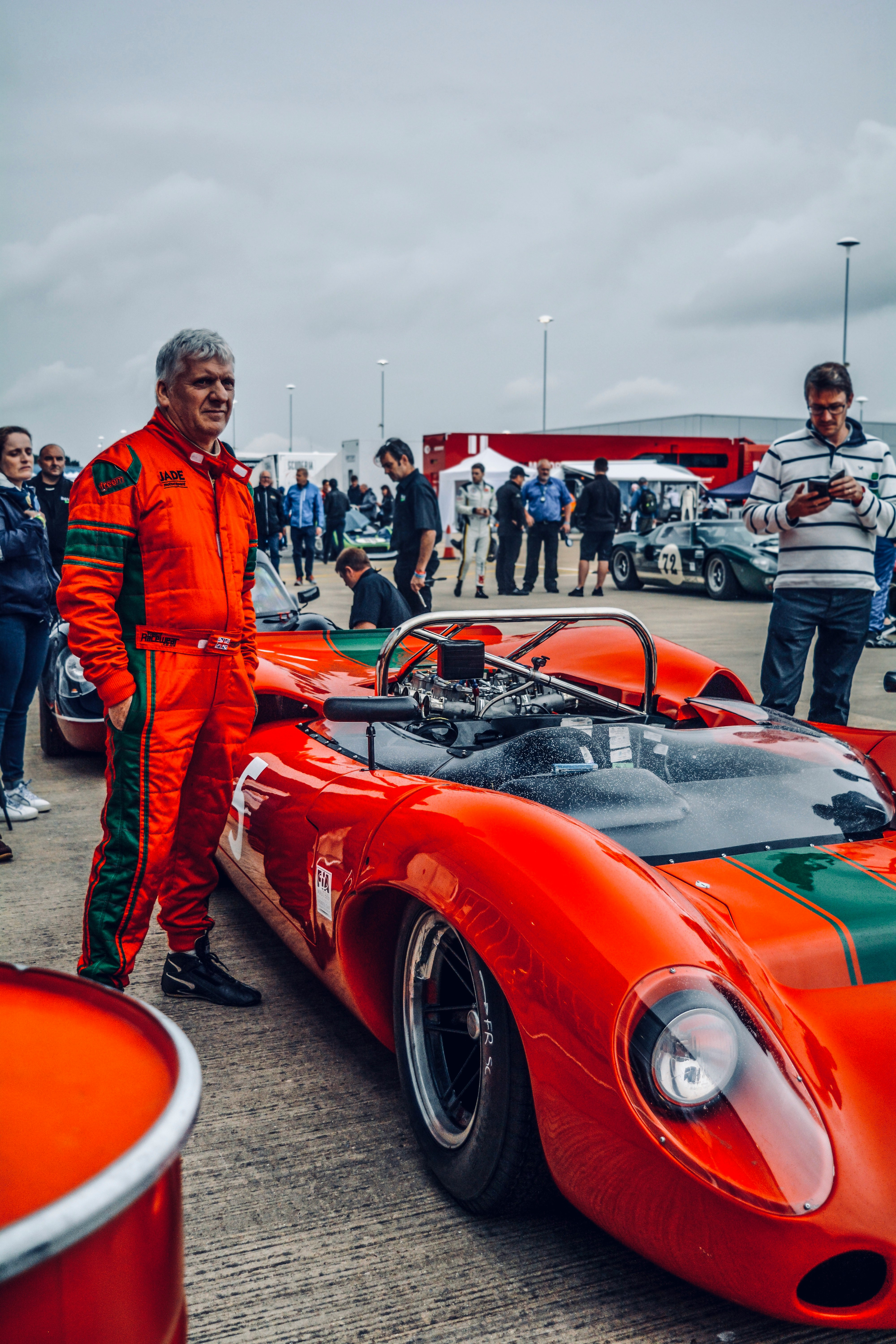 man standing beside red sports car