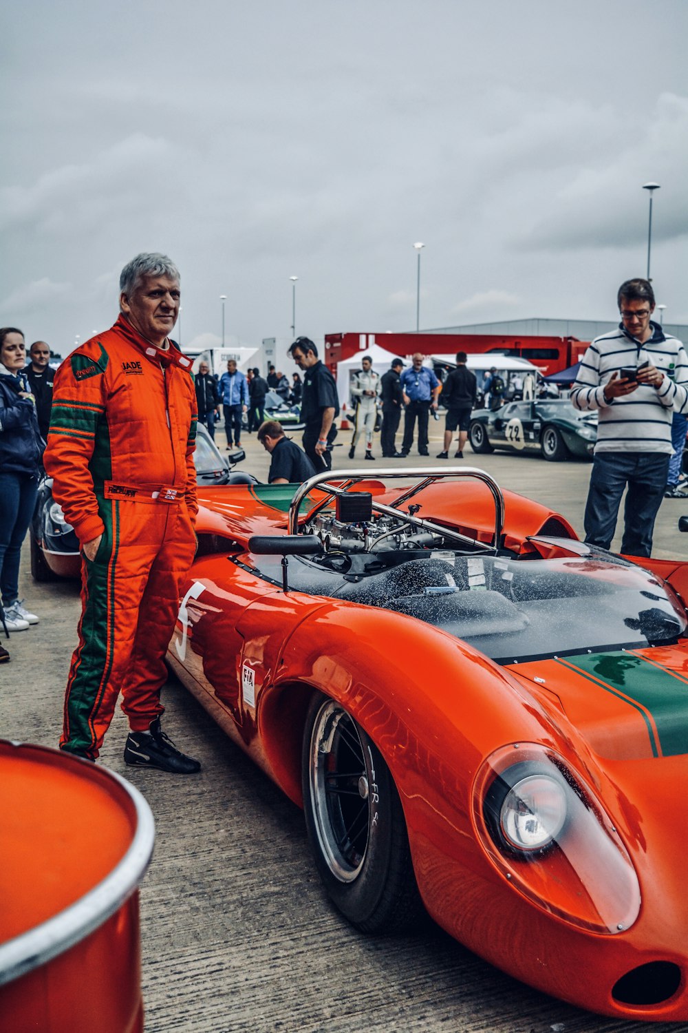 man standing beside red sports car