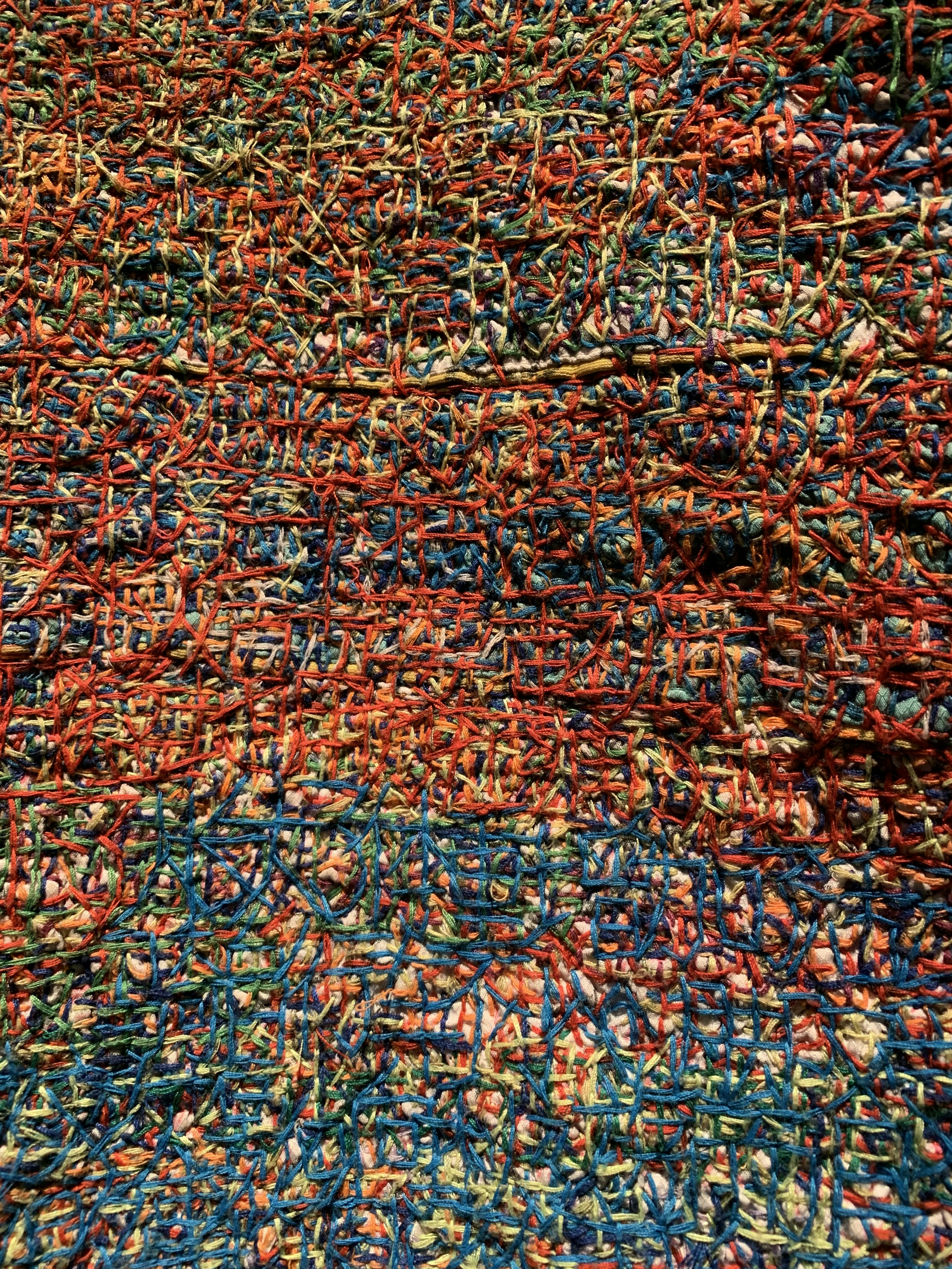 Close-up of woven fabric texture showing intricate thread patterns, colorful textile