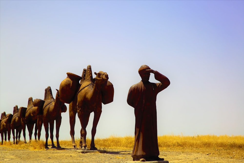 statue of man and camels during daytime