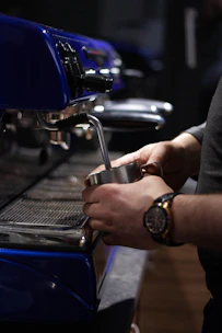 Close-up view of milk steaming technique being demonstrated on espresso machine.