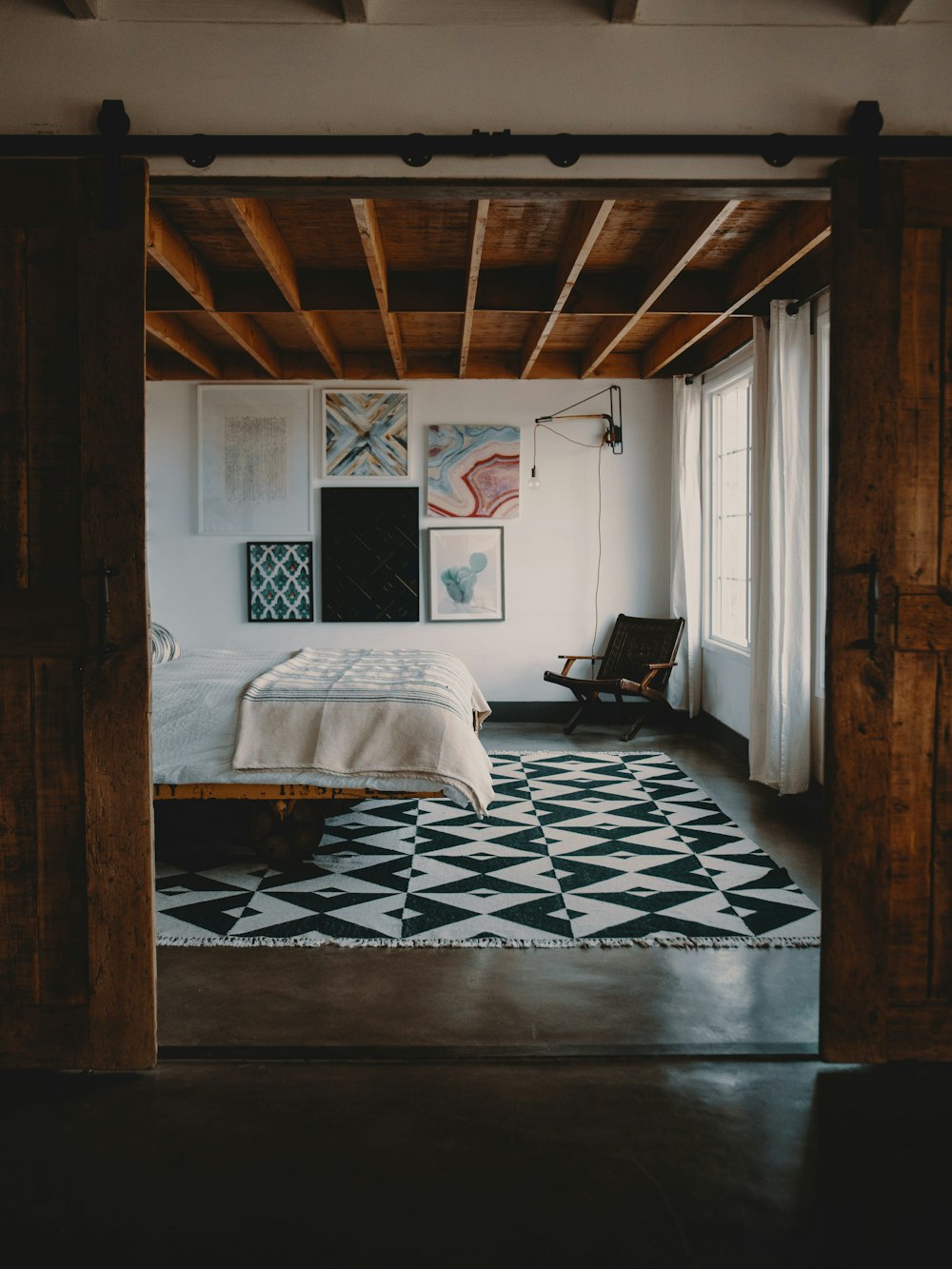 wooden armchair on corner in front of bed